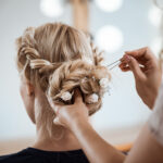 female hairdresser making hairstyle to blonde girl in beauty salon.